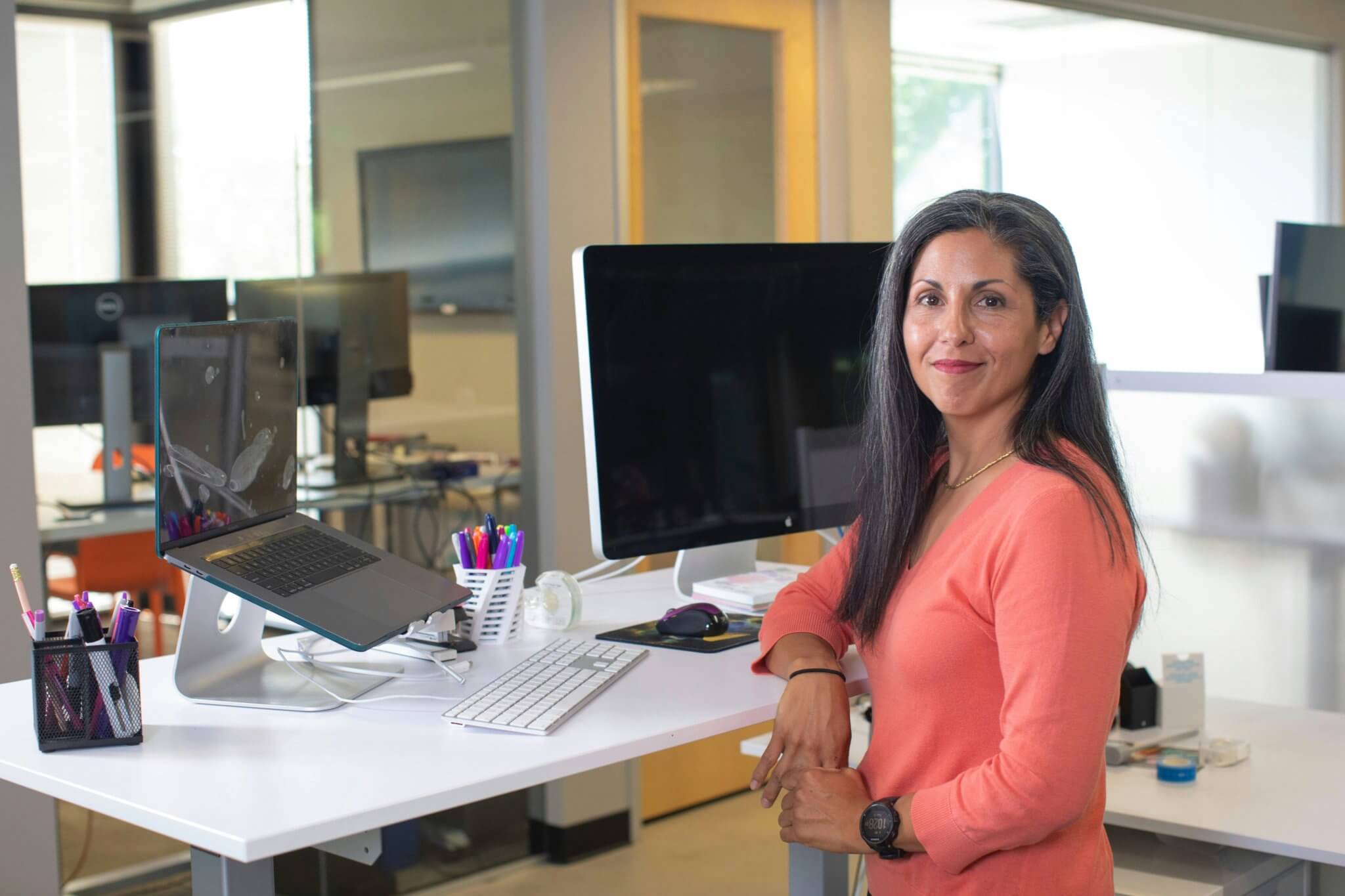 Woman in orange shirt at her standing desk working