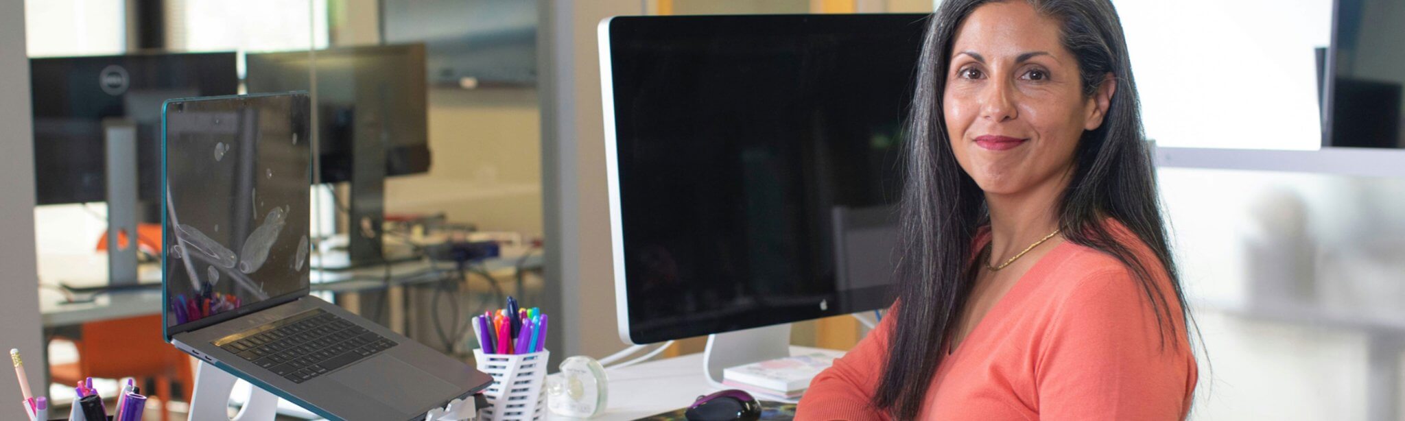 Woman in orange shirt at her standing desk working