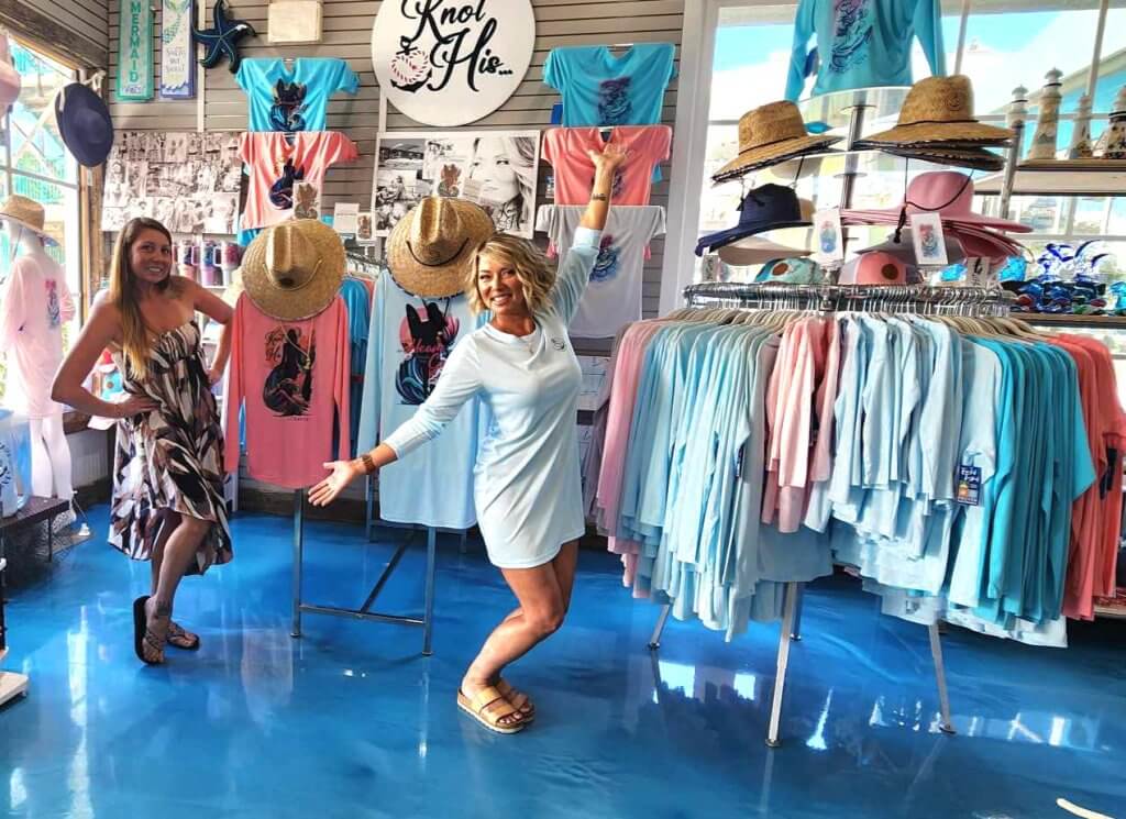 Jeannie Pope, owner of Knot His 850, poses with wholesale customer Toni LaBatt in front of Jeannie's UV-protection apparel on display at Harborwalk Marina in Destin, Florida.