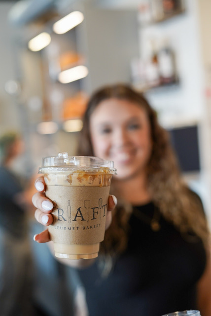 Image of a Craft Gourmet Bakery employee displaying one of their hand-crafted coffees.