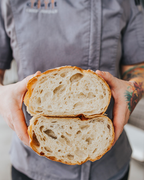 Craft Gourmet Bakery employee holding a loaf of red sea sourdough bread.